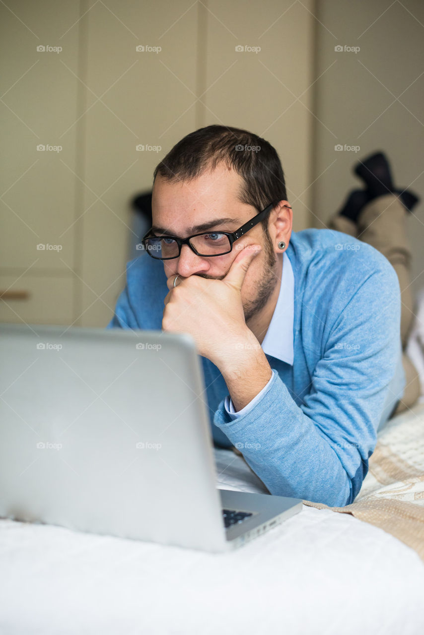 man working on laptop at home on the bed