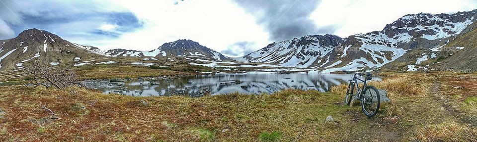 Panoramic of bike in mountains by secluded lake