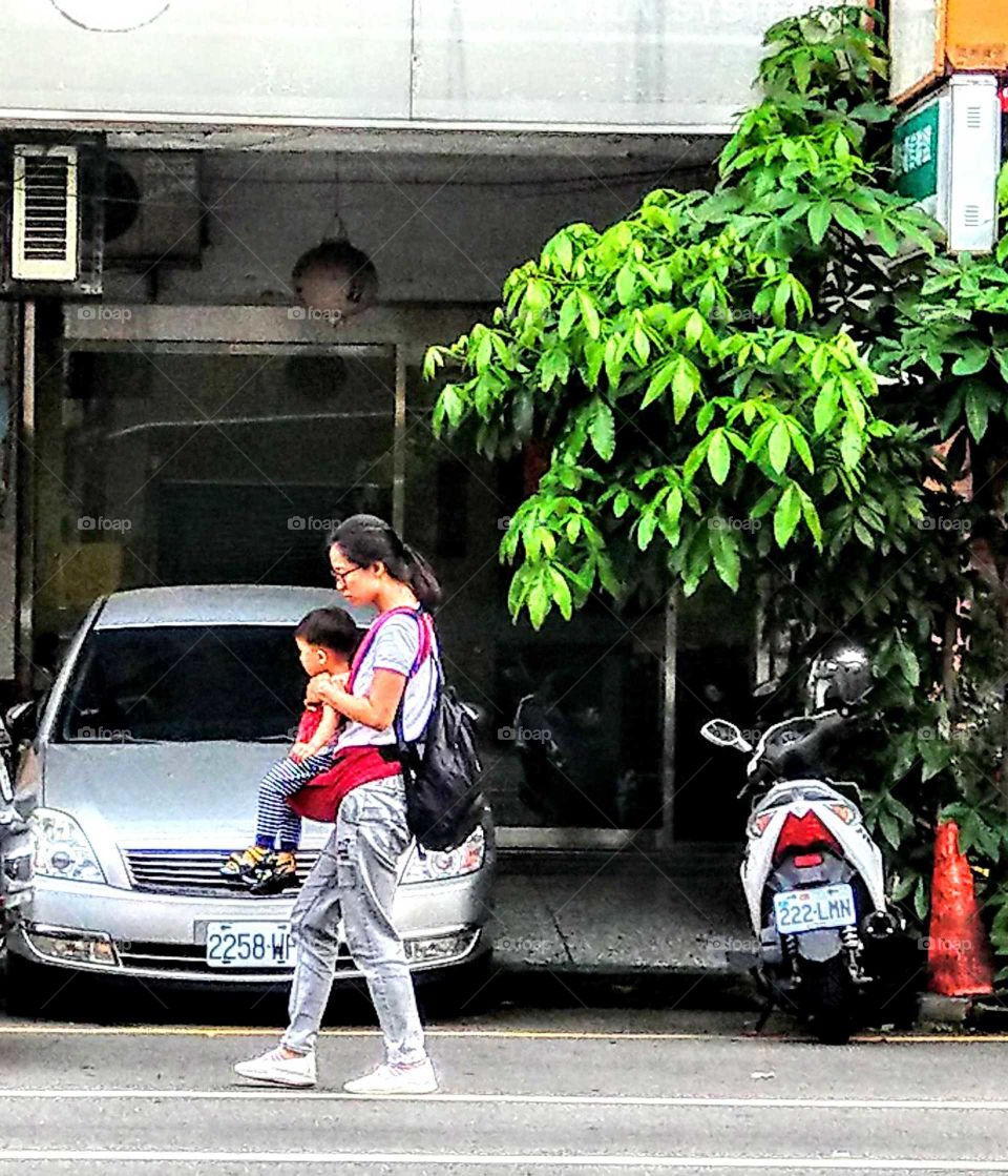 A mother's love for her child. carrying her child looked a little hard in the street. great mother's love!