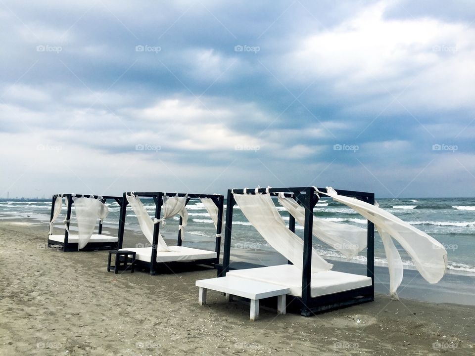 Empty baladachins on the beach on a stormy day with dark clouds