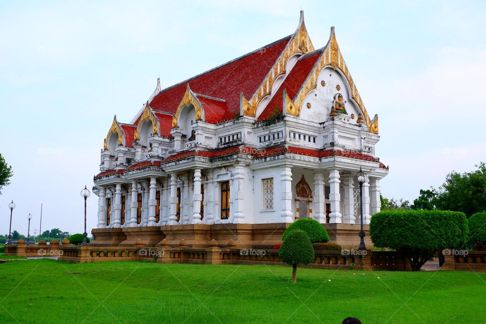 white church building with brown base surrounded by green grass and trees