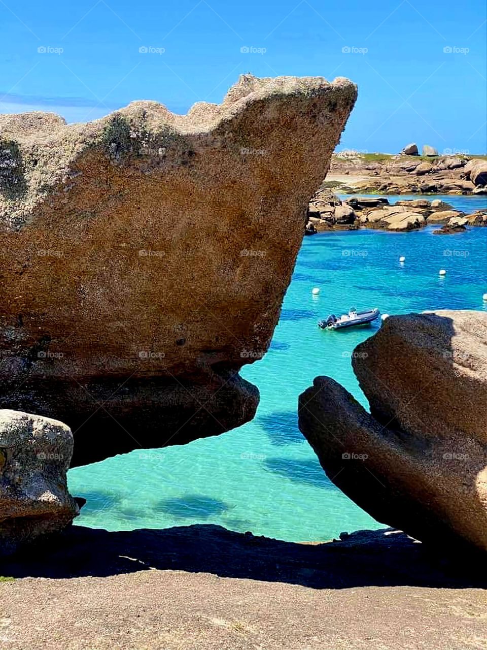 View of the coast, the sea and the boats through the rocks in Trégastel