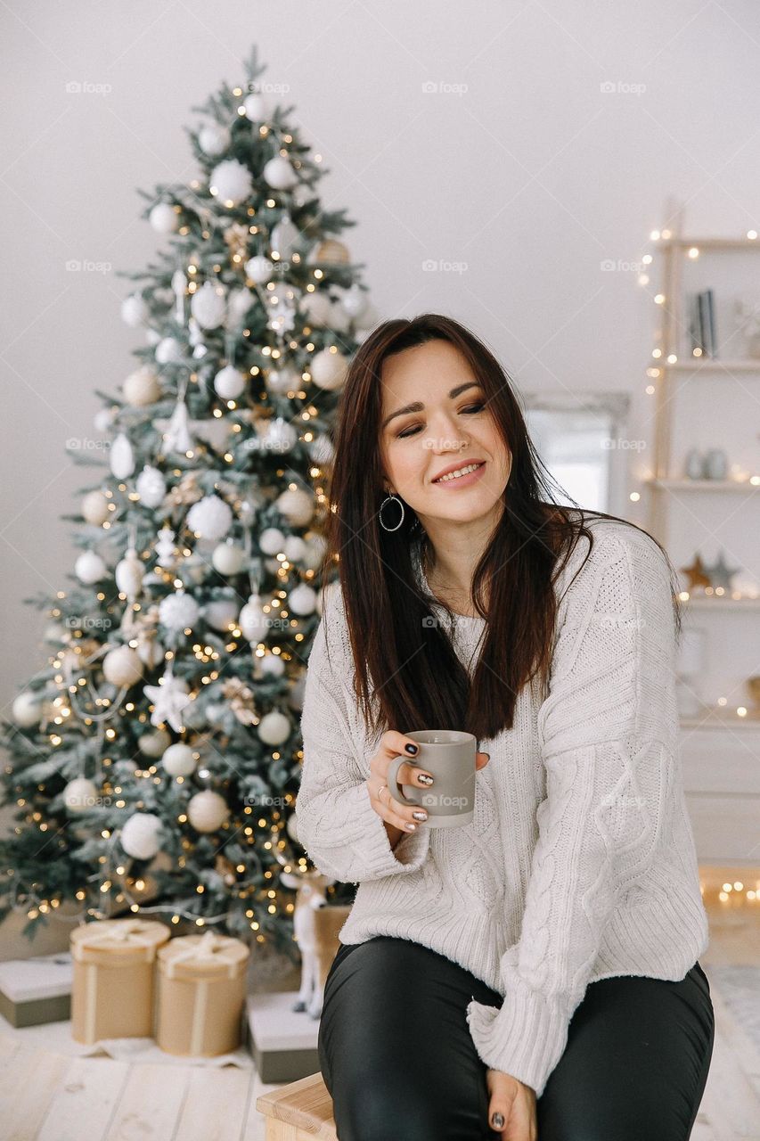 Brunette girl holding cup of coffee and close eyes. New Year Eve