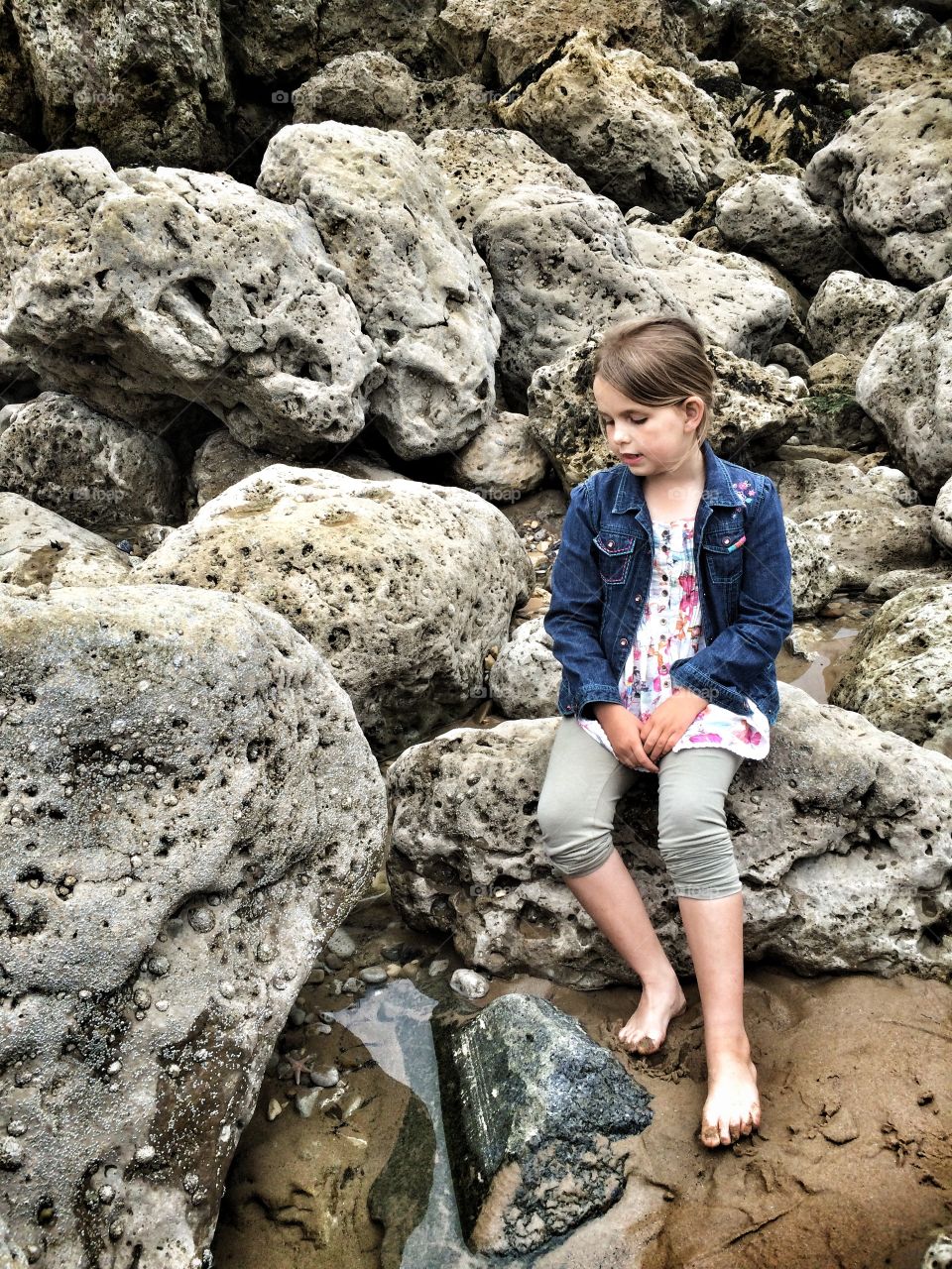 Blonde girl sitting on rock at beach