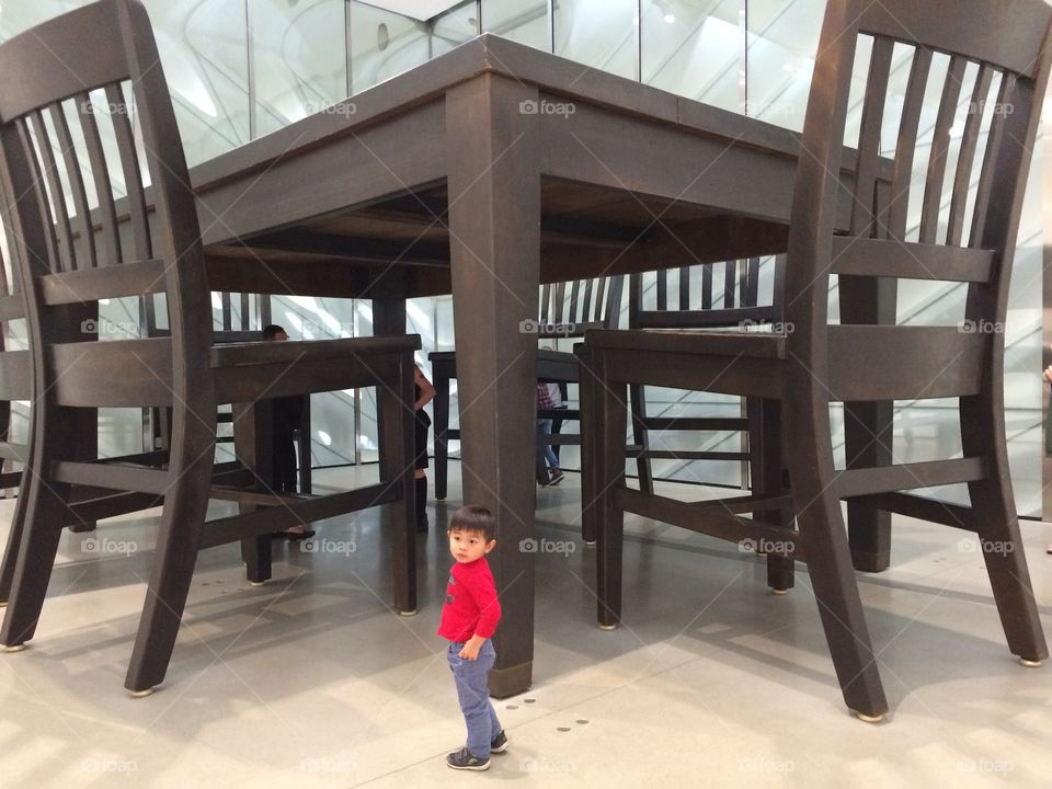 Small boy standing near big chair and table