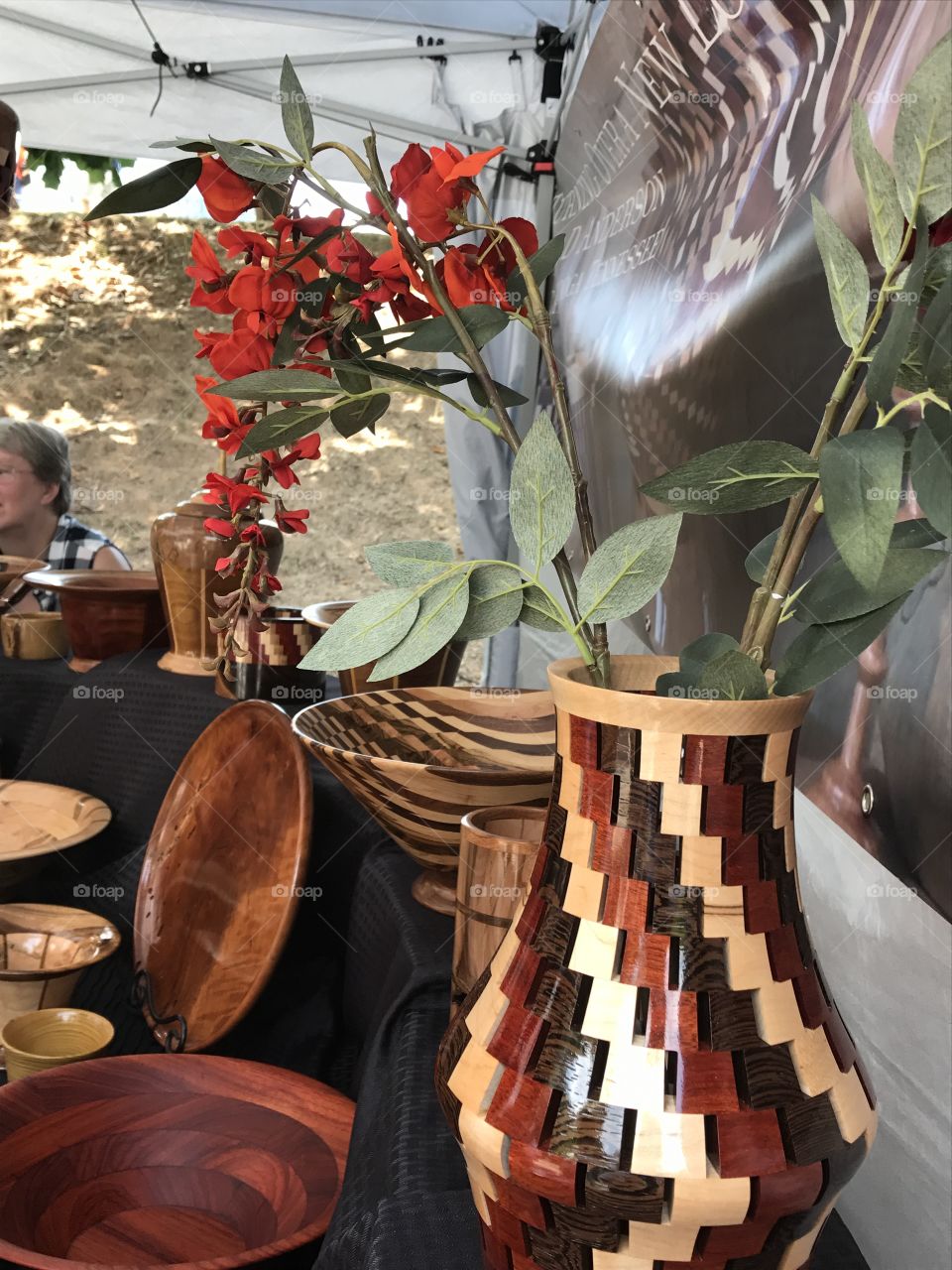 Various handmade wooden plates, bowls, and vases, with red flowers