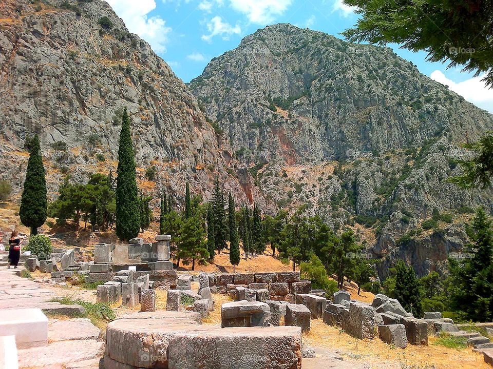 City or village.  Open spaces.  Greece.  Delphi.  Among the rare green trees lie the ruins of the ancient temple of Apollo.  Mount Parnassus rises in the background.