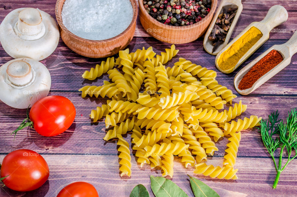 Raw pasta with ingredients and wooden accessories