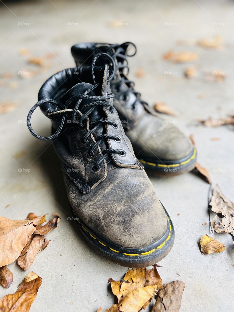 Overhead closeup of thirty year old classic Doc Martens boots on a cement floor with autumn leaves. Symbol of workmanship and lasting quality. @9bachelors Instagram