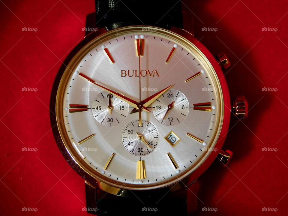 Gold Bulova watch on red background! Bulova, an American brand, is known for its innovation, craftsmanship and advanced technology. The Bulova Brand is a recognized leader in diamonds and high performance sport timekeeping, with a wide range of watches for dress, and sport and causal wear. No wrist should be without a Bulova watch!