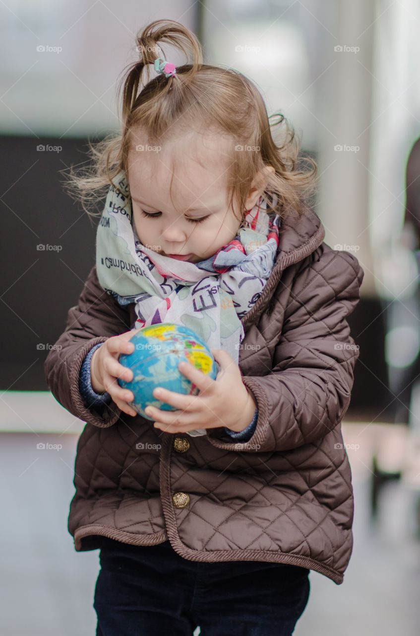 Cute little girl holding world globe on her hand