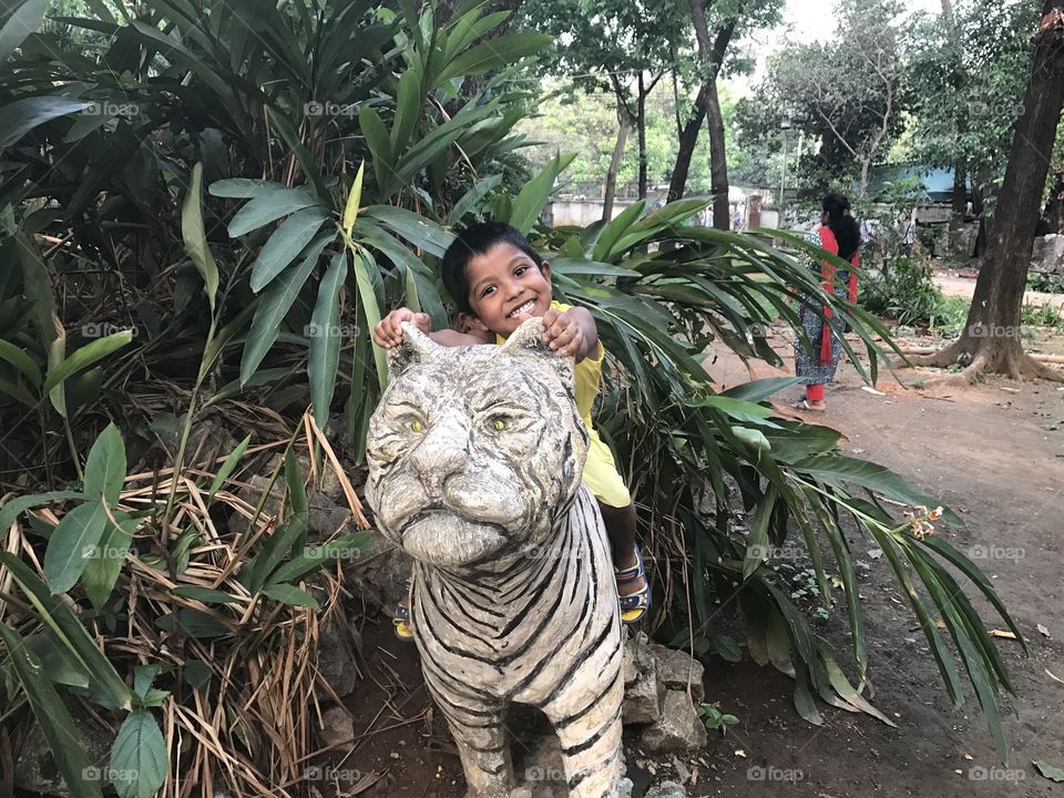 Indian girl sitting on statue of tiger