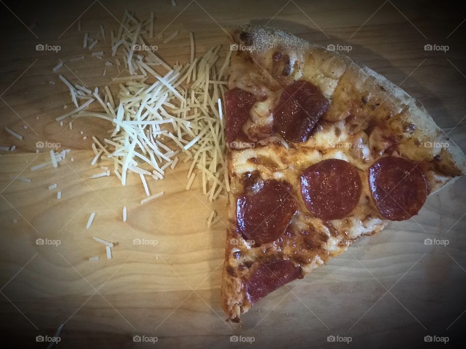 Golden pepperoni pizza and sprinkled cheese displayed on a cutting board 