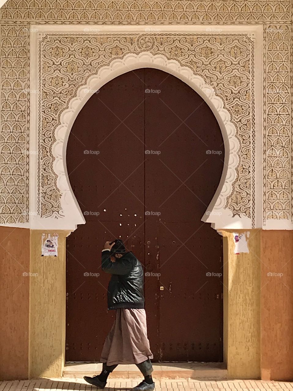 Man walking in front of the doors of the Mosque in Ouarzazate in morocco after the prayer