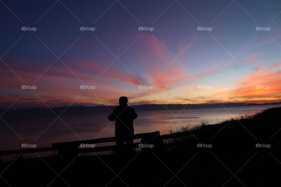 Man taking photo of beautiful sunset over the ocean