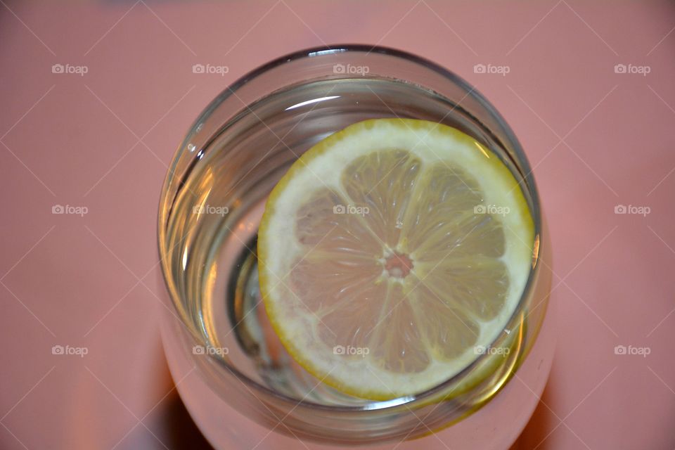 Overhead view of a sparkling glass of lemon water with a lemon slice floating on top