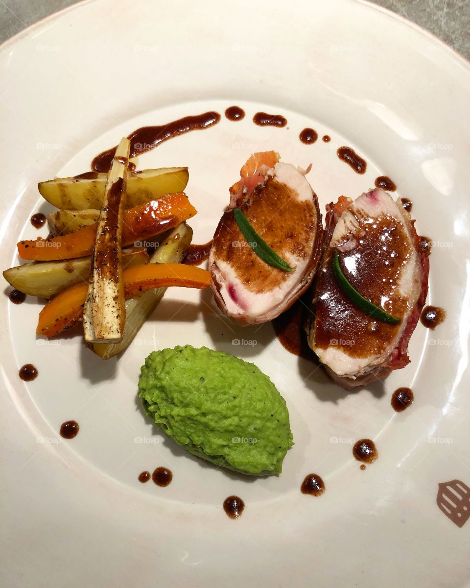 Prosciutto rolled chicken breasts served with, pea puree, roasted vegetables, and some balsamic reduction