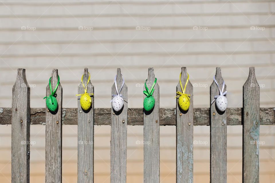 Colourful eggs are hanging on the fence. Easter decorations 