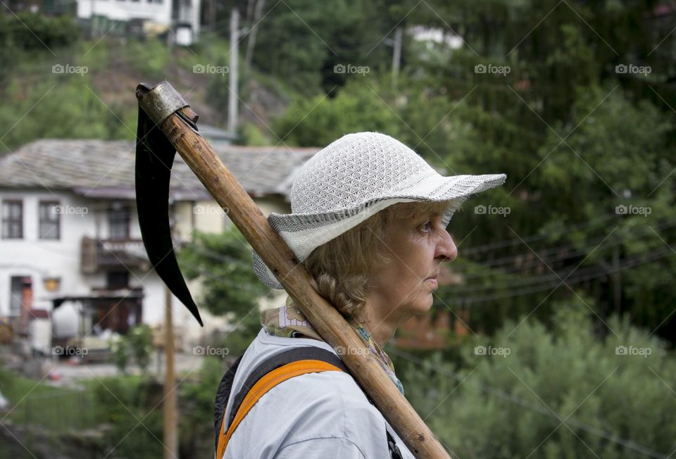 A woman holds scythe outdoor