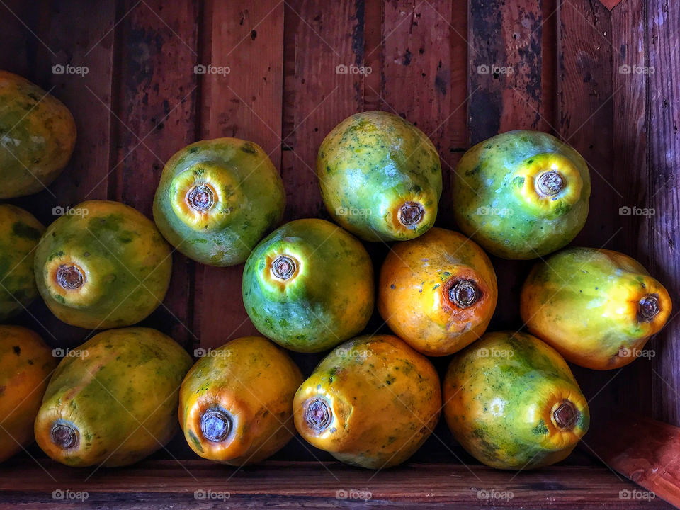 Papayas stacked in a wooden box at a farmer’s market 