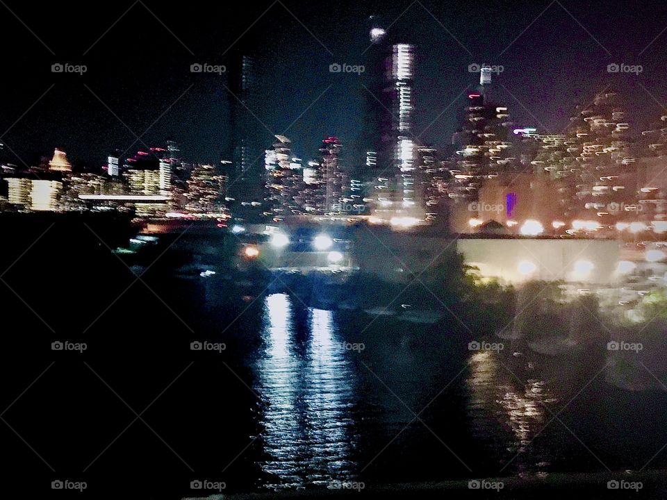 An arial view of the ocean photographed in October 2020 from the Pulaski Bridge in Long Island City, Queens, NY with the illuminated cityscape of Queens, the Manhattan skyline in the distance and the Empire State Building mirrored in the water🍍
