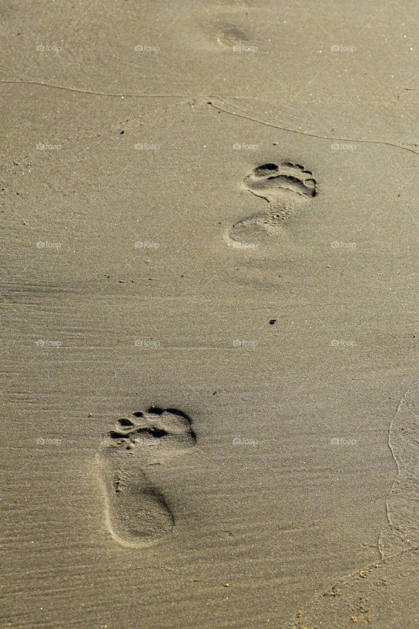 woman footprints in sand on the seashore