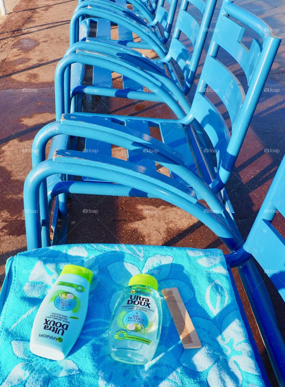 Garnier eau de coco shampoo and conditioner on a blue beach towel and chairs.