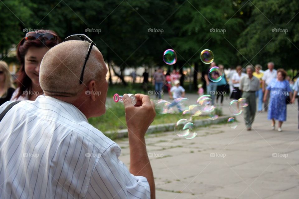 Elder man blowing bubbles like a child 