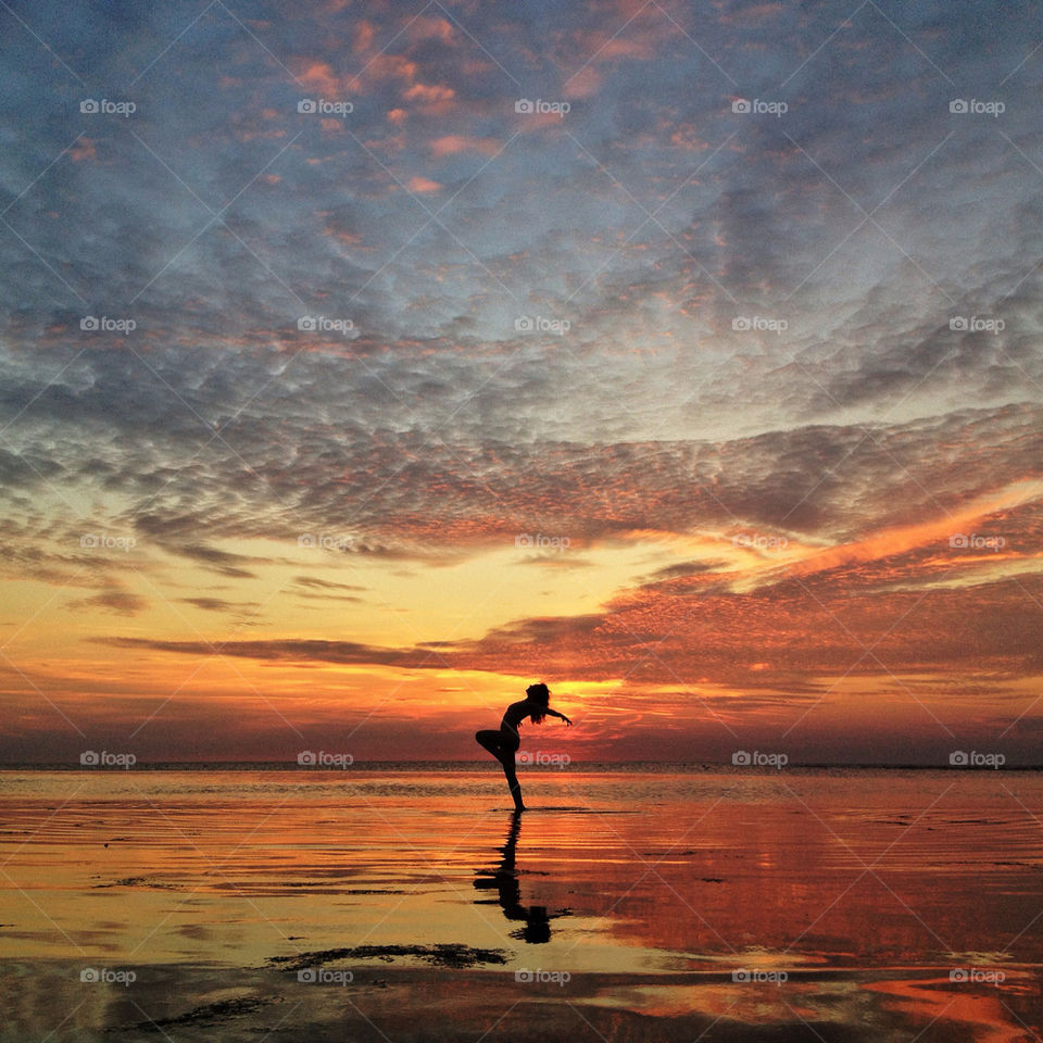 Silhouette of a woman posing on beach at sunset
