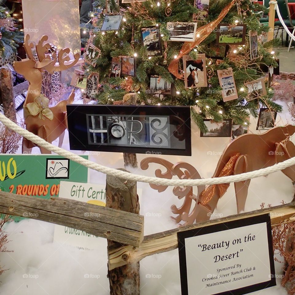 A beautiful Christmas tree decorated with horse photographs part of an indoor display of wooden fences for the holiday season. 