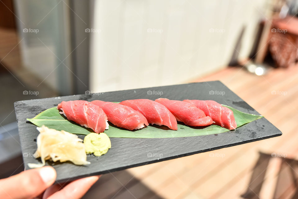 Person holding tuna sushi dish