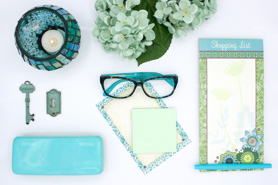 Teal and turquoise flat lay items on white desk 