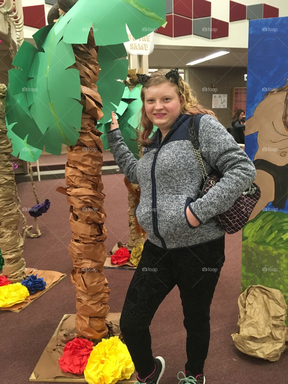 She poses by a paper palm tree for the Tarzan musical at a high school.