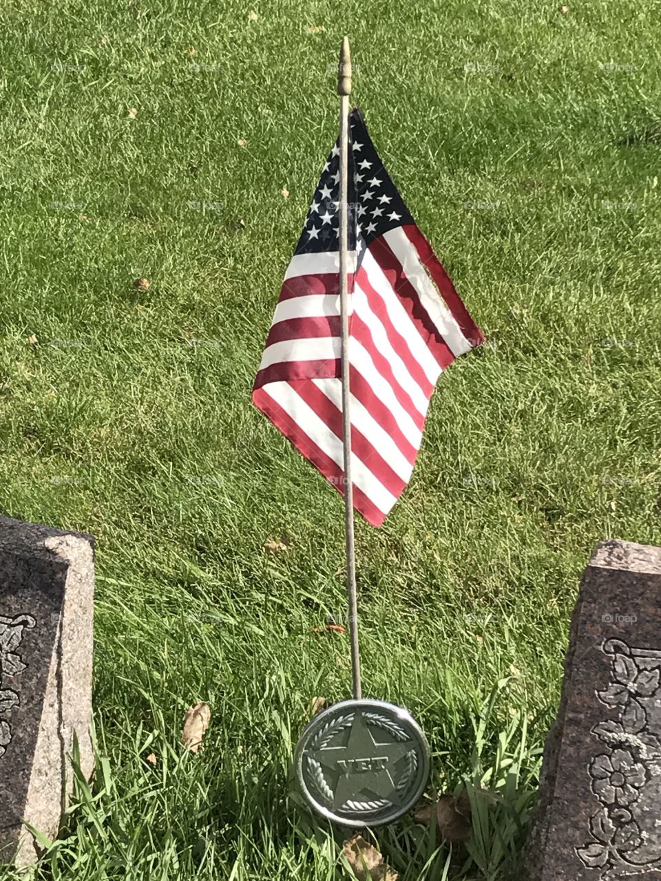 A U.S. Veteran's flag posted between two gravestones.