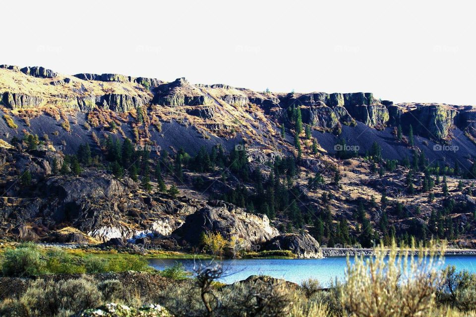 Enhanced photo of the coulee area in Washington. Vibrant trees and bright blue lake. 