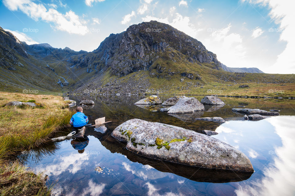 Boy sitting on rock in lake