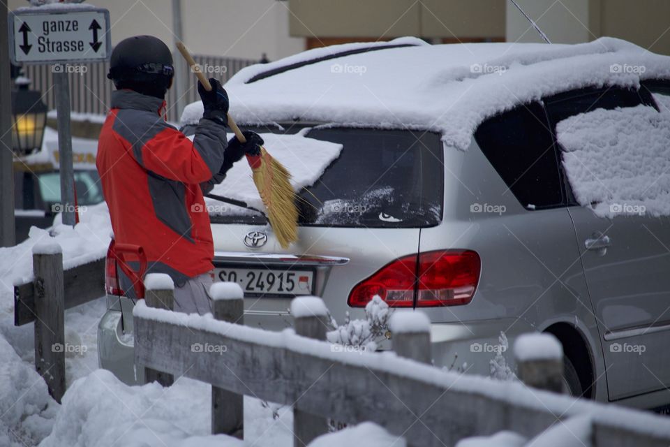 Man Cleaning Snow Off His Car