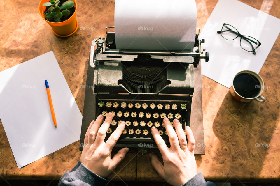 A young writer is writing his new book on his old typewriter.