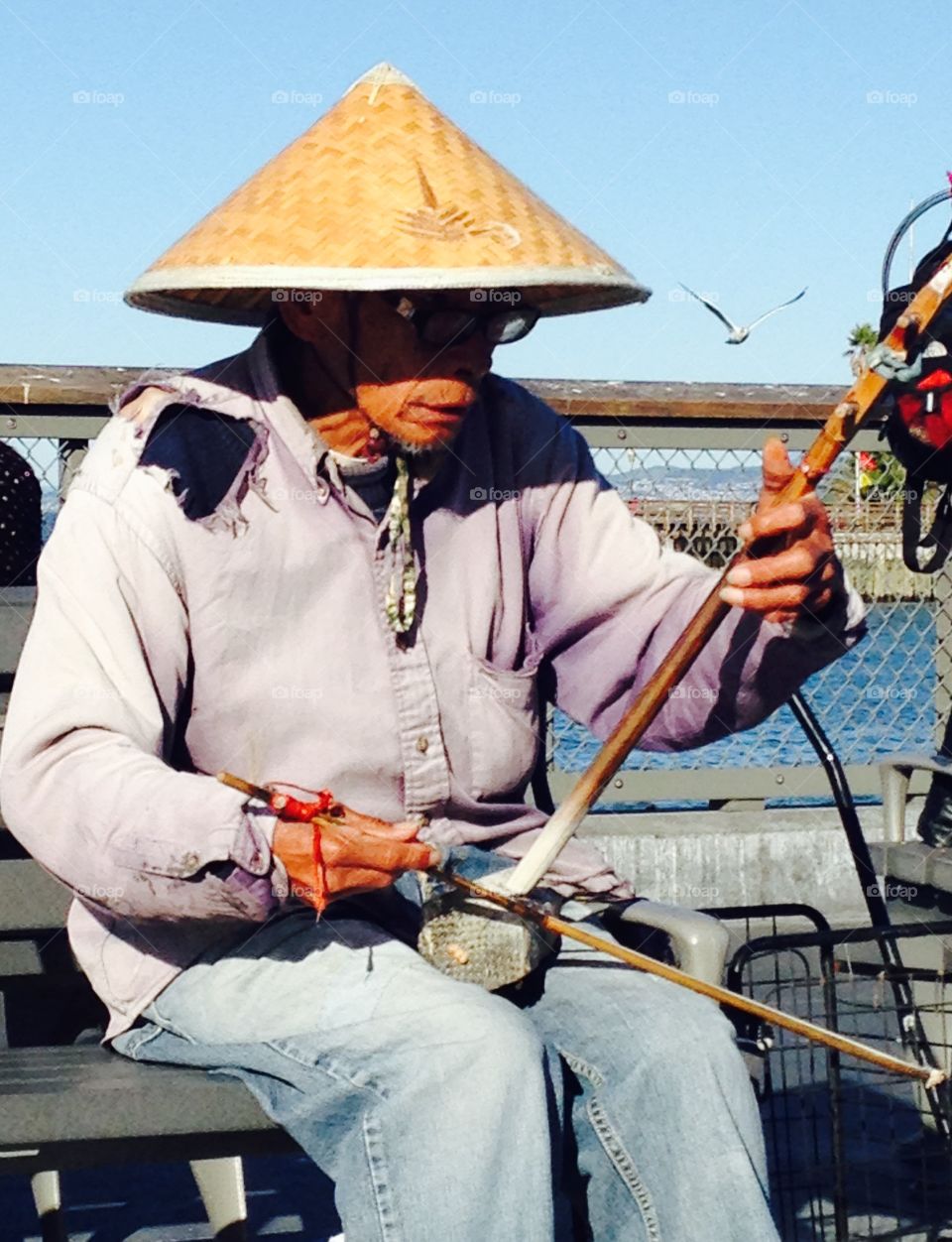 A busker playing. A man sitting on a bench in San Francisco playing his instrument