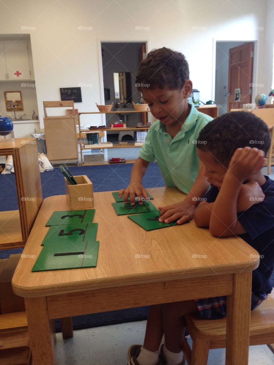 Two boys playing with numbers in classroom.