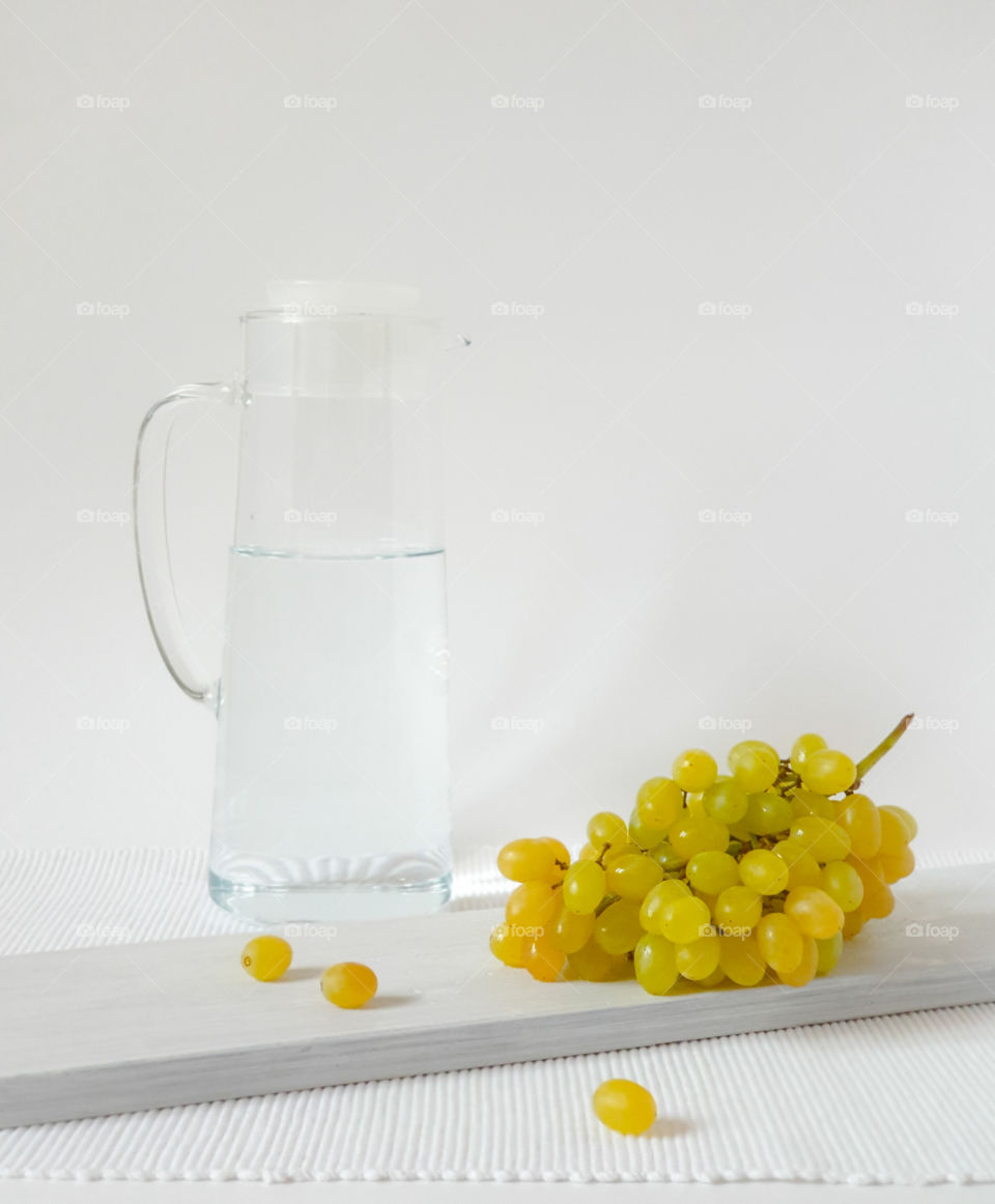 Still life in a rustic style.  Green grape quiche with a glass jug of water on a wooden board and textured white napkin.  Tasty healthy snack