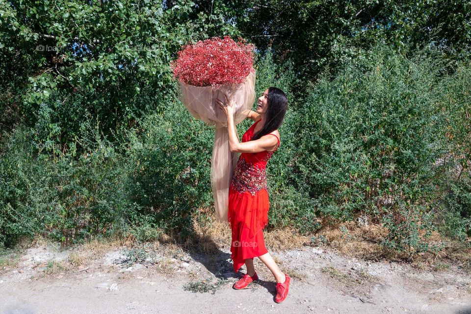 Woman Dances with a Large Bouquet of Red Flowers