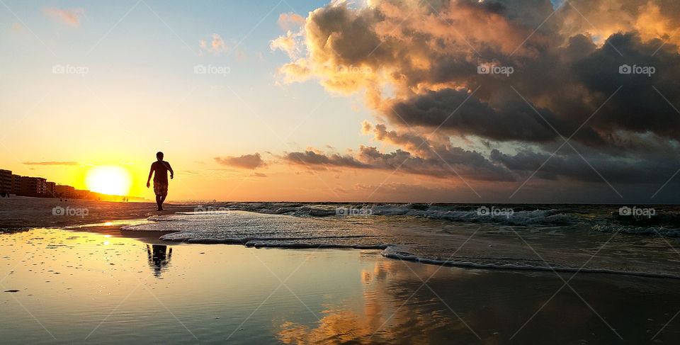 tourist on vacation walking down beach at sunrise.