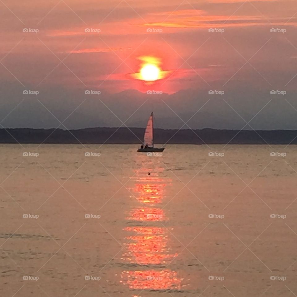 Sunset sailboat. Fiery Seattle sunset  due to wildfires with sailboat in reflection 