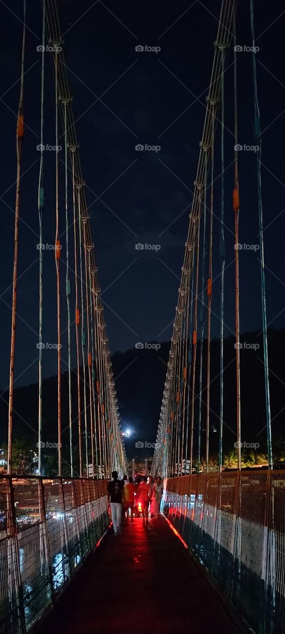 Ram Jhula, an iron suspension bridge across the river Ganges, located 3 kilometres north-east from the town Rishikesh in the Indian state of Uttarakhand.