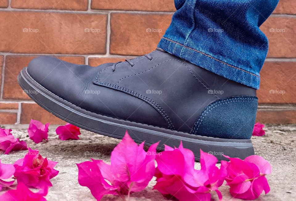 the passage of a person in blue boots, with bougainvillea petals on the ground