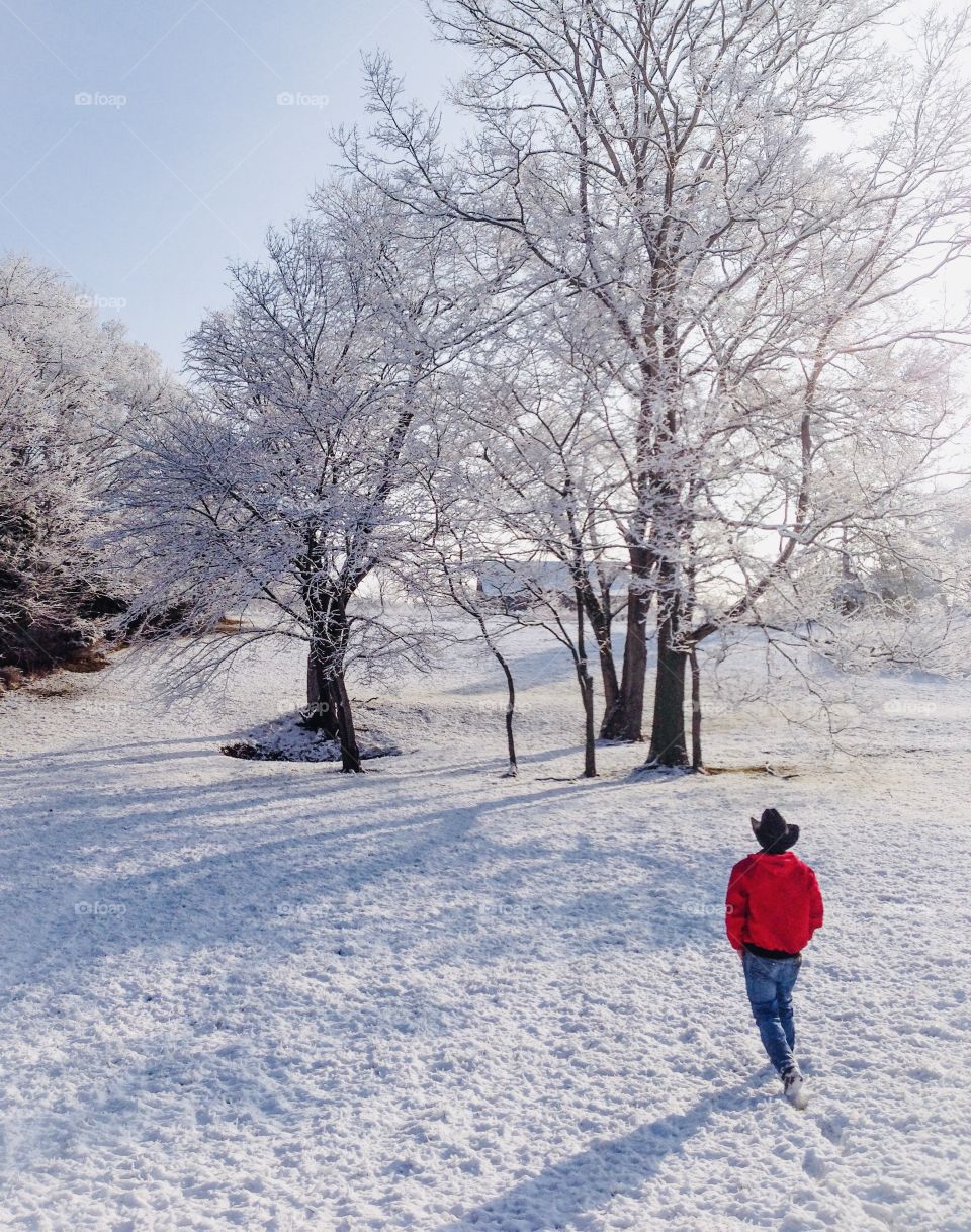 A man with a red jacket walking in the snow