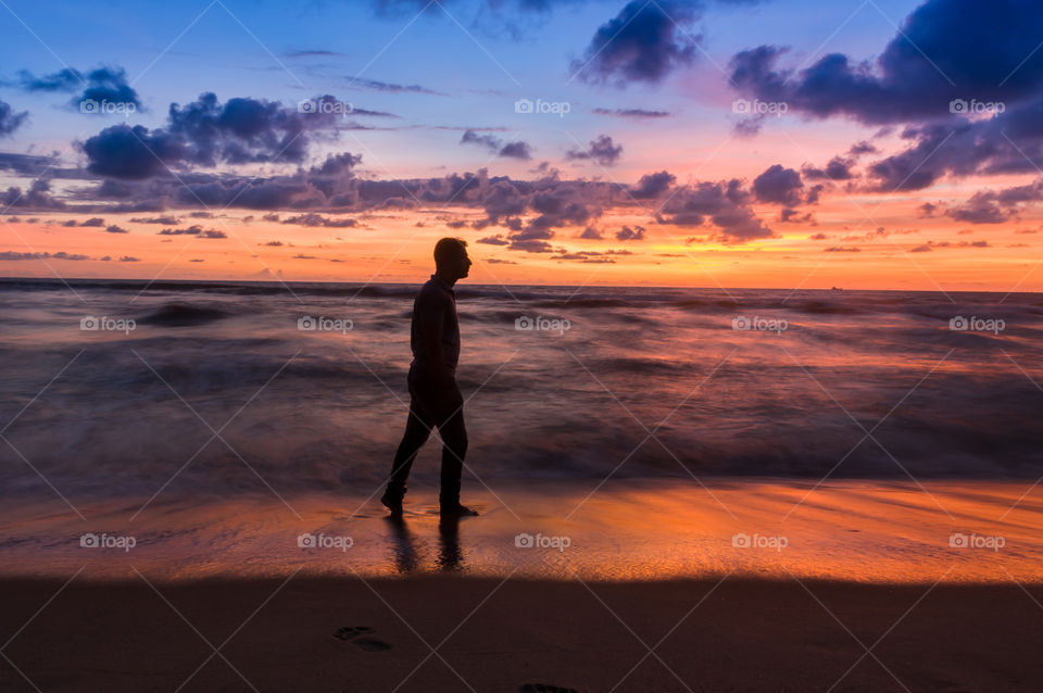 Man walking on the beach and enjoying beautiful sunset.