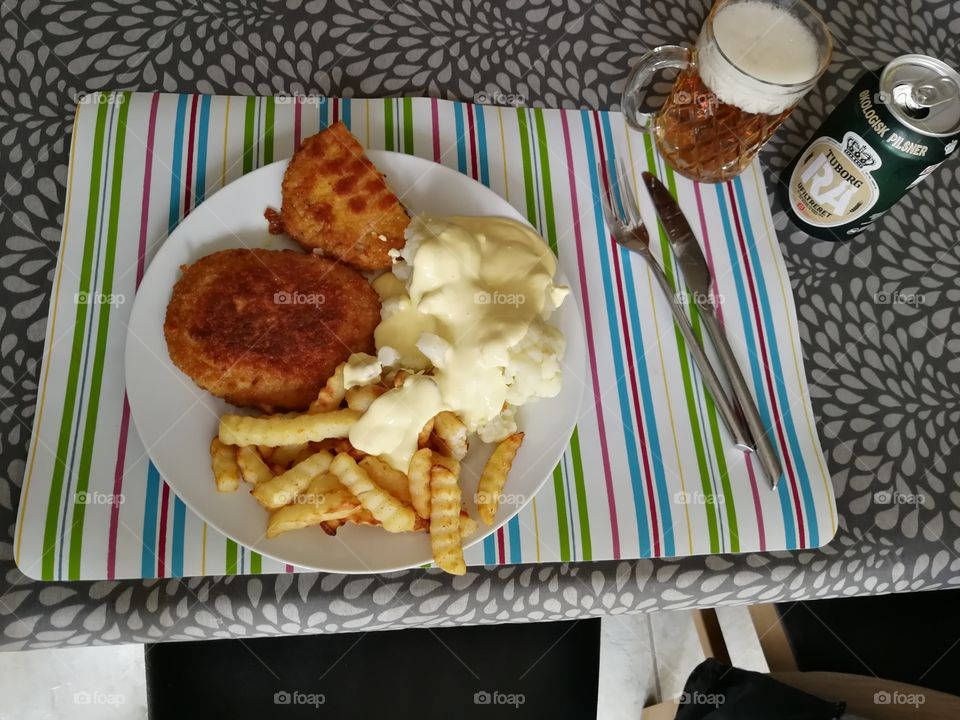 Breaded pollock, French fries, cauliflower with hollandaise sauce. In addition, a cold beer, Pilsener brewing style.