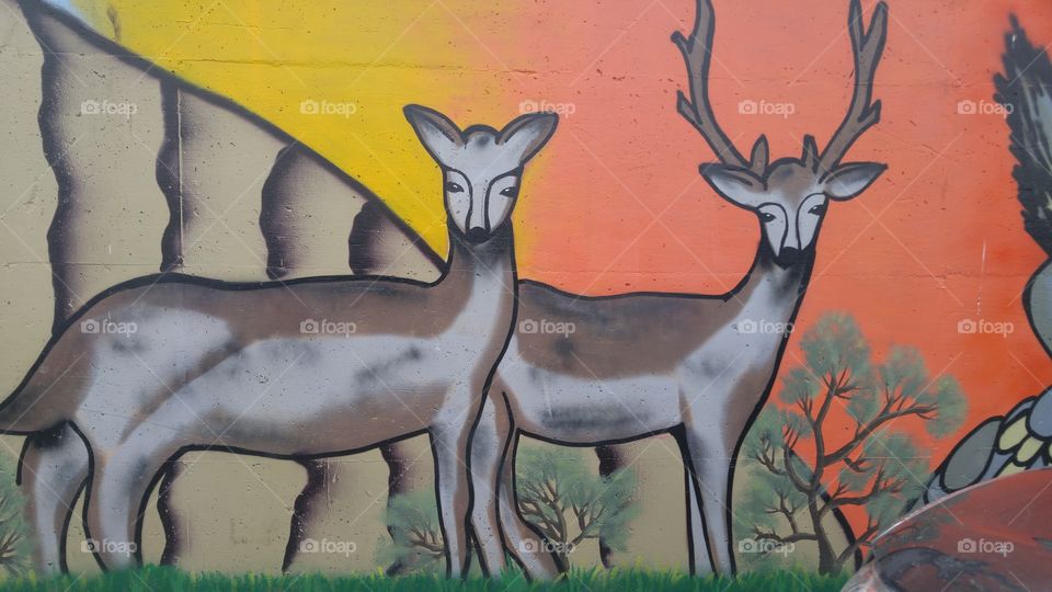 Parking lot wall art of deer standin in side biew.